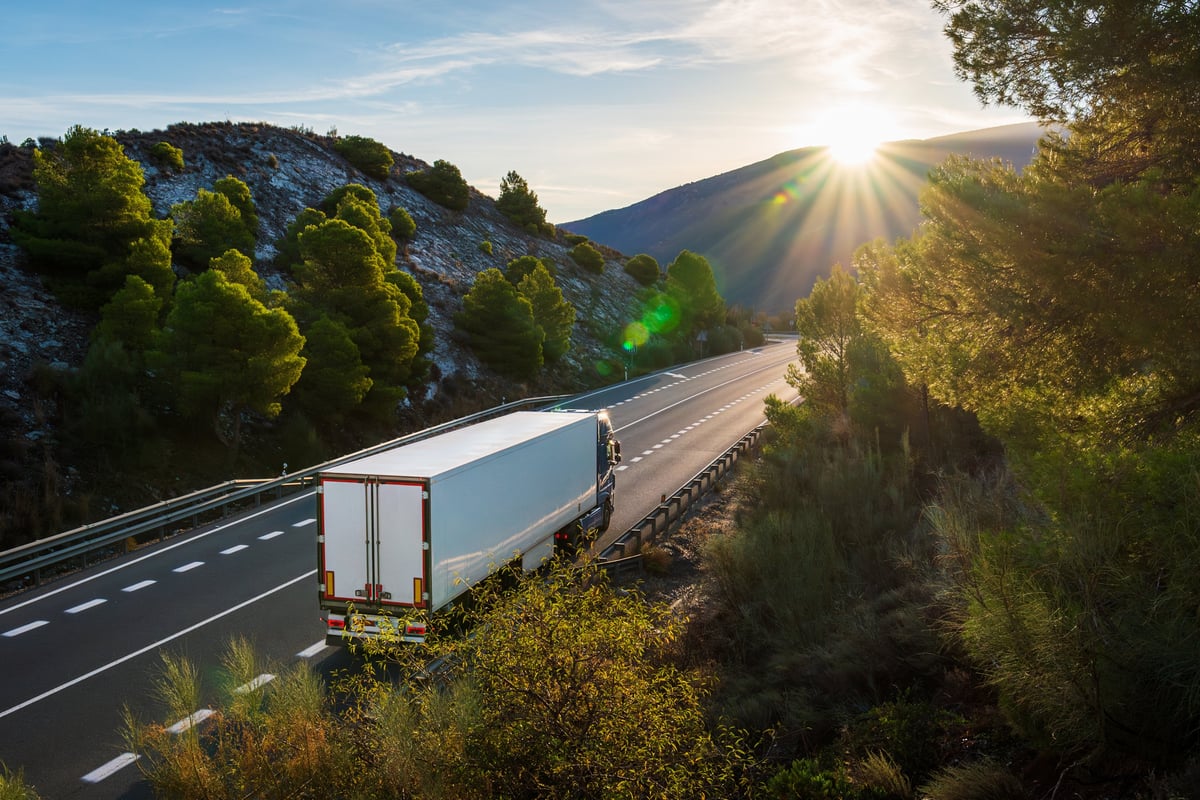 Semi truck driving along an open highway through the mountains
